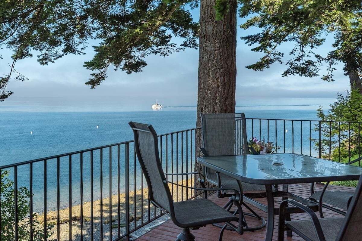 A deck with a table and chairs overlooking a body of water with a boat in the distance.