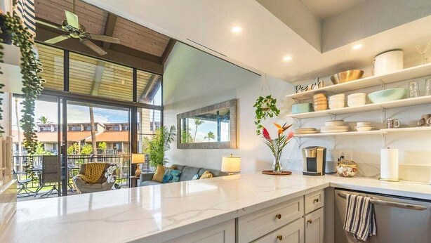 A modern kitchen with a large island, built-in appliances, and a balcony with outdoor seating. - Perch - Luana Kai Loft: Captivating Modern 2-Bedroom for a Dream Vacation (Kihei)
