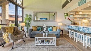 A living room with a sofa, armchair, coffee table, and bar area with stools. - Perch - Luana Kai Loft: Captivating Modern 2-Bedroom for a Dream Vacation (Kihei)