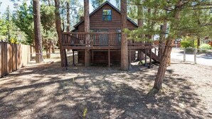 A wooden cabin with a deck, surrounded by tall trees. - Barrett Cottage | Dog-Friendly | BBQ Grill | Quiet and Peaceful (Big Bear)