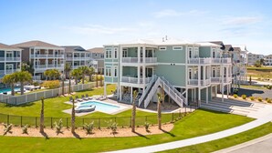 A multi-story hotel with a swimming pool, outdoor seating, and a well-maintained lawn.