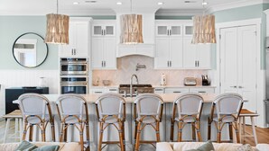 A modern kitchen with white cabinets, a central island with bar stools, and pendant lighting.