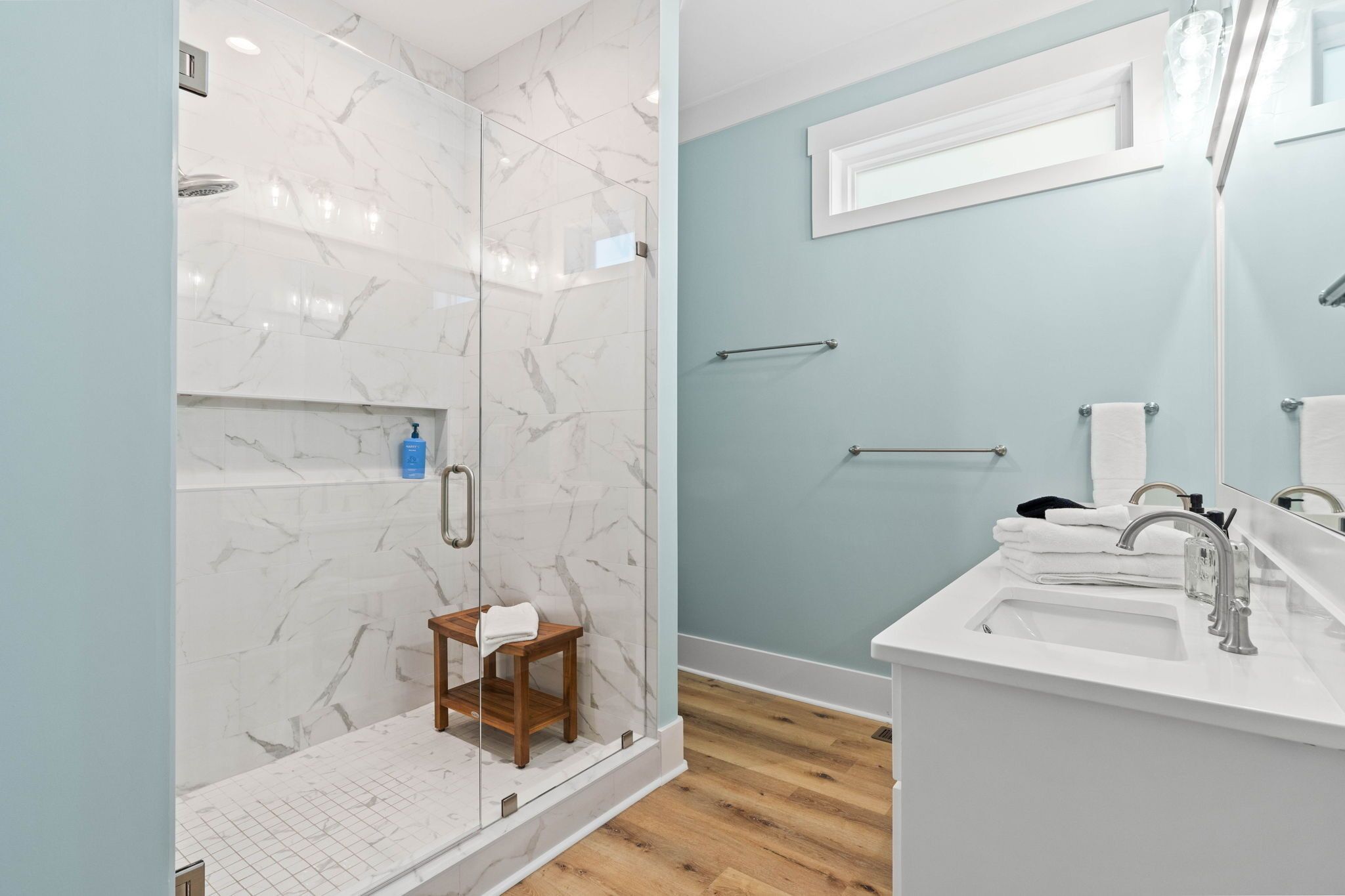 A modern bathroom with a glass-enclosed shower, a white sink, and a mirror.