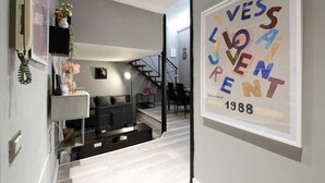 Un interior moderno con una escalera que conduce a un comedor, una obra de arte enmarcada en la pared y un estilo decorativo minimalista.