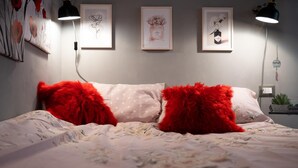Un dormitorio con una cama, almohadas rojas y tres cuadros en la pared.