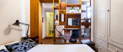 A bedroom with a bed, a desk, a chair, a lamp, and a wardrobe.