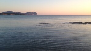 A calm sea with distant rocky formations and a clear sky.
