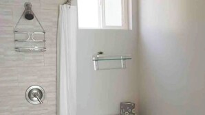 Une salle de bain avec une douche, des toilettes et une petite étagère au-dessus des toilettes.