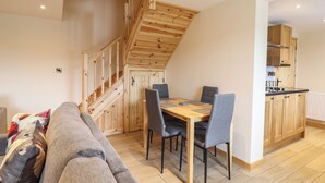 Un intérieur moderne avec un escalier en bois, un coin repas comprenant une table et des chaises, et une cuisine dotée de meubles en bois.