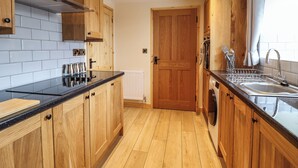 Une cuisine moderne avec des meubles en bois, un plan de travail noir, un évier en acier inoxydable et un four encastré.