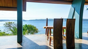 A modern outdoor seating area with a view of the sea and hills. - Inlight Lombok Eco Resort (Kuta)
