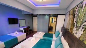 A hotel room with two single beds, a desk, a TV, and a bathroom visible through an open door. - Bona Sera Hotel (Istanbul)