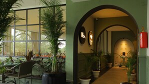 Un pasillo con plantas en macetas, un extintor y un banco.