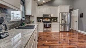 Una cocina moderna con armarios blancos, electrodomésticos de acero inoxidable y suelo de madera.