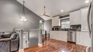 Una cocina moderna con armarios blancos, lavavajillas de acero inoxidable y piso de madera.