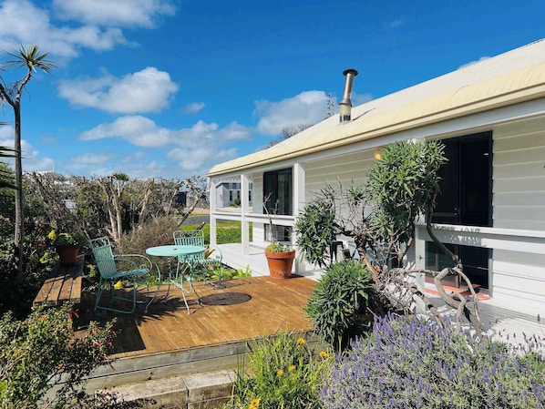 A house with a wooden deck, a green outdoor chair, and various potted plants.