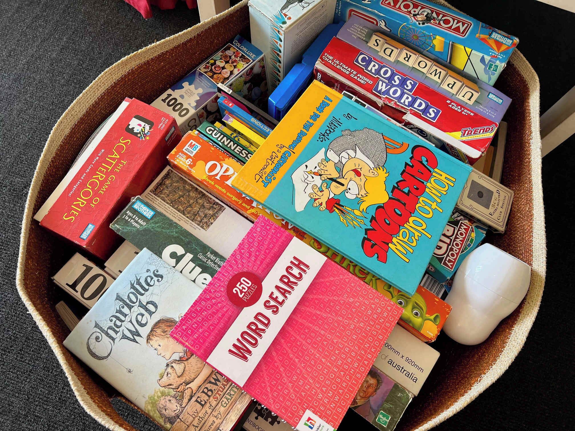 A variety of board games and puzzles in a basket.