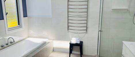 Un baño con bañera, ducha y un perchero para toallas.