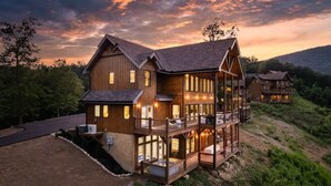 A large wooden house with multiple levels, large windows, and a balcony. - Laughing Pines - Indoor pool & theater room (Smoky Mountains)