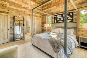 A wooden cabin bedroom with a four-poster bed, a nightstand, a lamp, and a framed picture on the wall. - Luxury Cabin | Private Pool, Hot Tub & Theater (Smoky Mountains)