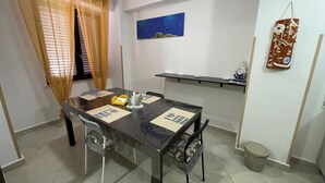 A dining area with a table set for two, a painting on the wall, and a shelf with items. - Cirismiro Torre Faro B&B  (Torre Faro)
