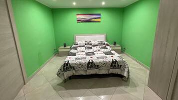Una camera da letto con pareti verdi, un letto con copriletto fantasia, un comodino e un quadro appeso al muro.