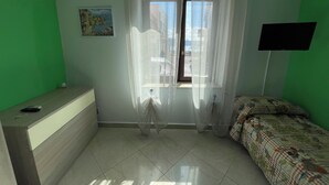 A room with a bed, a desk, a window with curtains, a painting on the wall, and a TV mounted on the wall. - Cirismiro Torre Faro B&B  (Torre Faro)