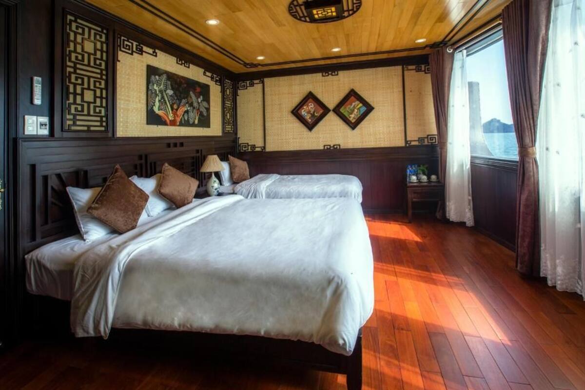Habitación de hotel con dos camas, suelo de madera y decoración de pared tradicional.
