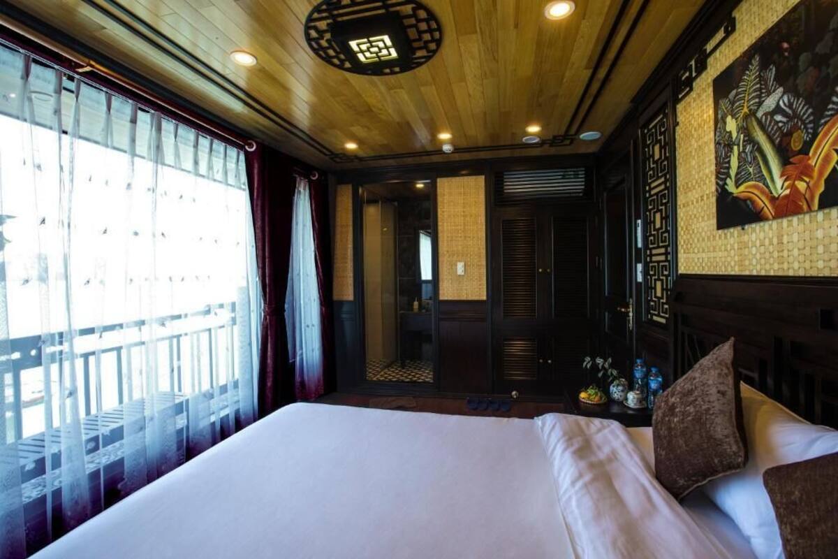 Habitación de hotel con una cama grande, techo de madera y vista a un balcón.