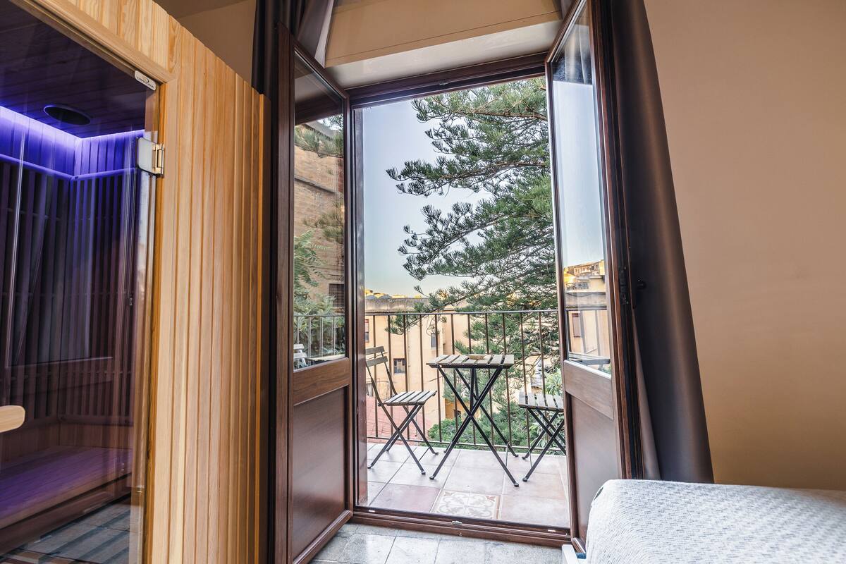 Et værelse med en skydedør, der fører ud til en balkon med bord og stole.