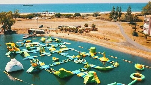 An aerial view of a water park with various water play structures and a sandy beach area.