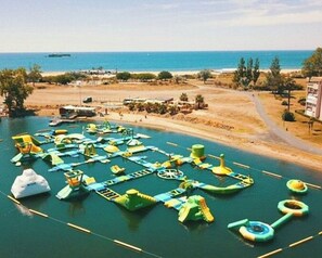 An aerial view of a water park with various water play structures and a sandy beach area.