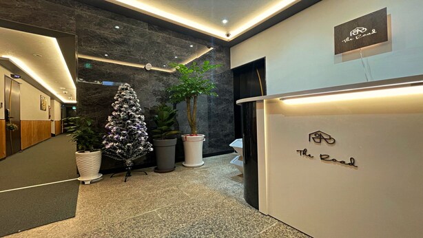 A modern reception area with a marble wall, potted plants, and a sign reading "The Road". - The Road (Seoul)