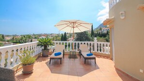 A balcony with two chairs, a table, and an umbrella, overlooking a scenic view. - Villa with panoramic views all inclusive in Denia (Denia)
