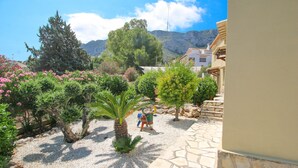 A courtyard with a palm tree, a statue, and a stone pathway. - Villa with panoramic views all inclusive in Denia (Denia)