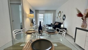 Un espace repas moderne avec une table en verre, des chaises blanches et une pièce maîtresse aux couleurs sombres.