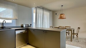 Une cuisine moderne équipée d’un lave-vaisselle, d’un grille-pain et d’un coin repas avec des chaises et une table en bois.