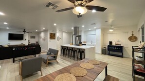 A modern kitchen with a central island, bar stools, and a dining table with woven placemats.
