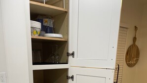 A kitchen with white cabinetry, a built-in toaster, and shelves holding plates and bowls.