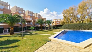 A swimming pool, palm trees, and a building with balconies. - MED 19 with paddel court (Denia)