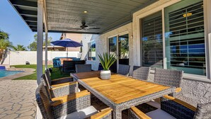 A covered patio with a wooden table and wicker chairs, a ceiling fan, and a view of the backyard. - 4BR w pool, fire pit, 3 king rooms (Glendale)