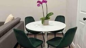 A small dining area with a round table and four green chairs. - The Monrow Suite! (West New York)