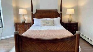 A four-poster bed with a wooden frame, two bedside tables with lamps, and a patterned throw blanket. - The Monrow Suite! (West New York)