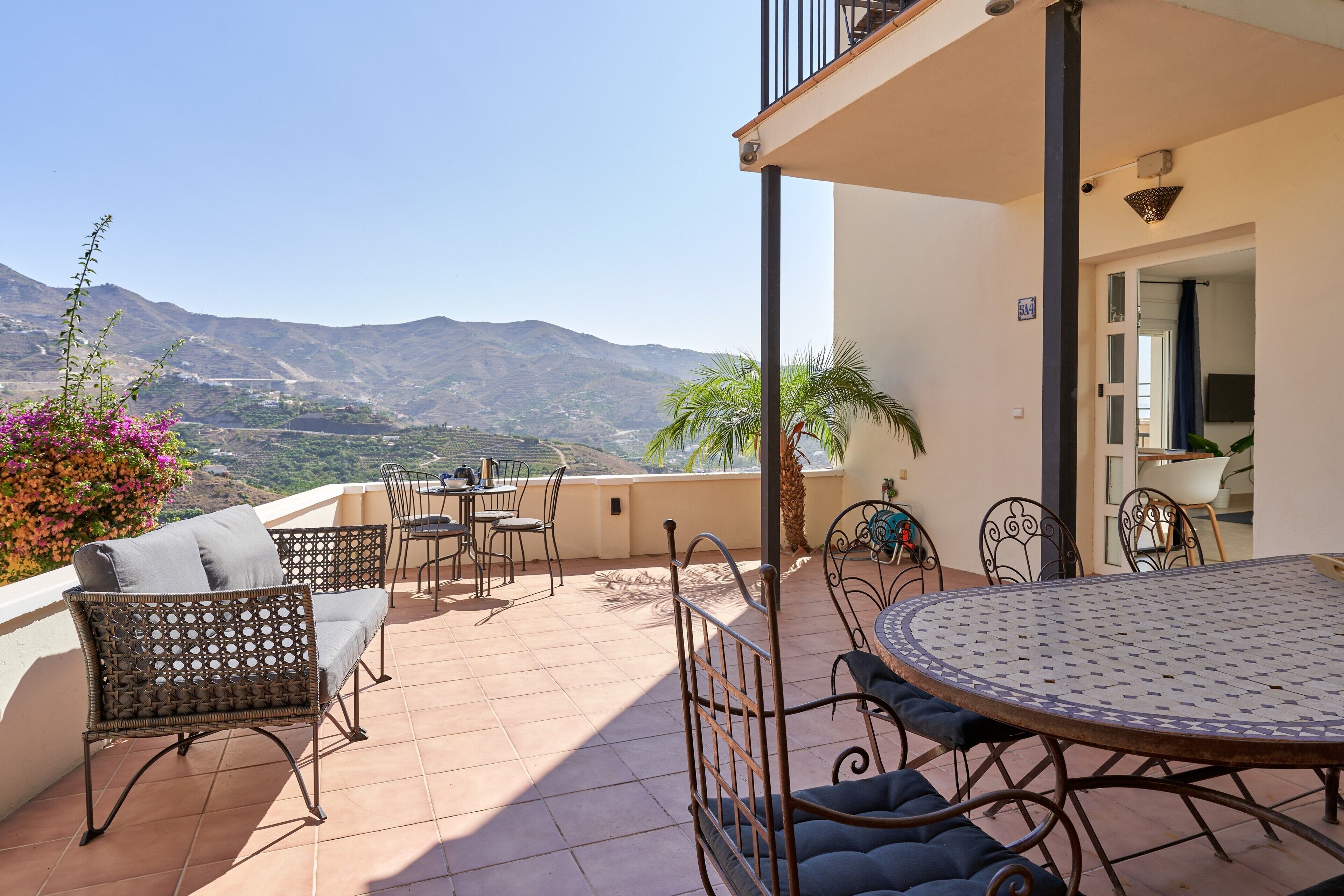 A terrace with outdoor furniture, a round table, and a view of mountains.