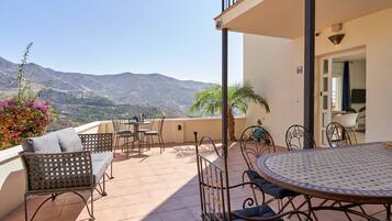 A terrace with outdoor furniture, a round table, and a view of mountains.