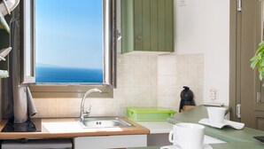Een keuken met een raam, een spoelbak, een vaatwasser en een groen aanrecht.