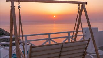 Un fauteuil suspendu en bois offrant une vue imprenable sur le coucher de soleil.