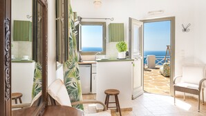 Een kamer met uitzicht op zee, een keukenhoek en een balkon met een stoel.