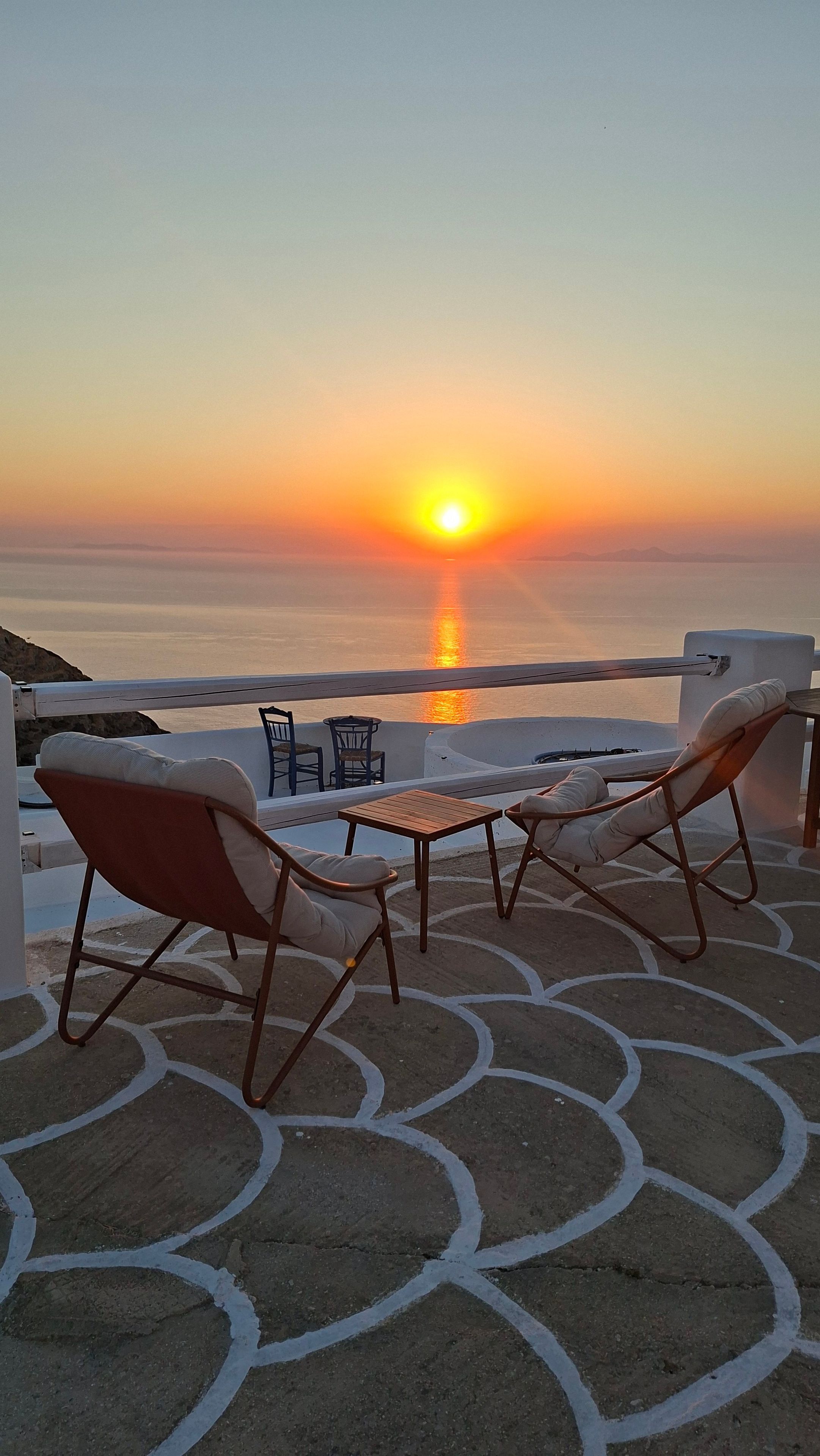 Una terrazza con posti a sedere all'aperto e vista sul tramonto sul mare.
