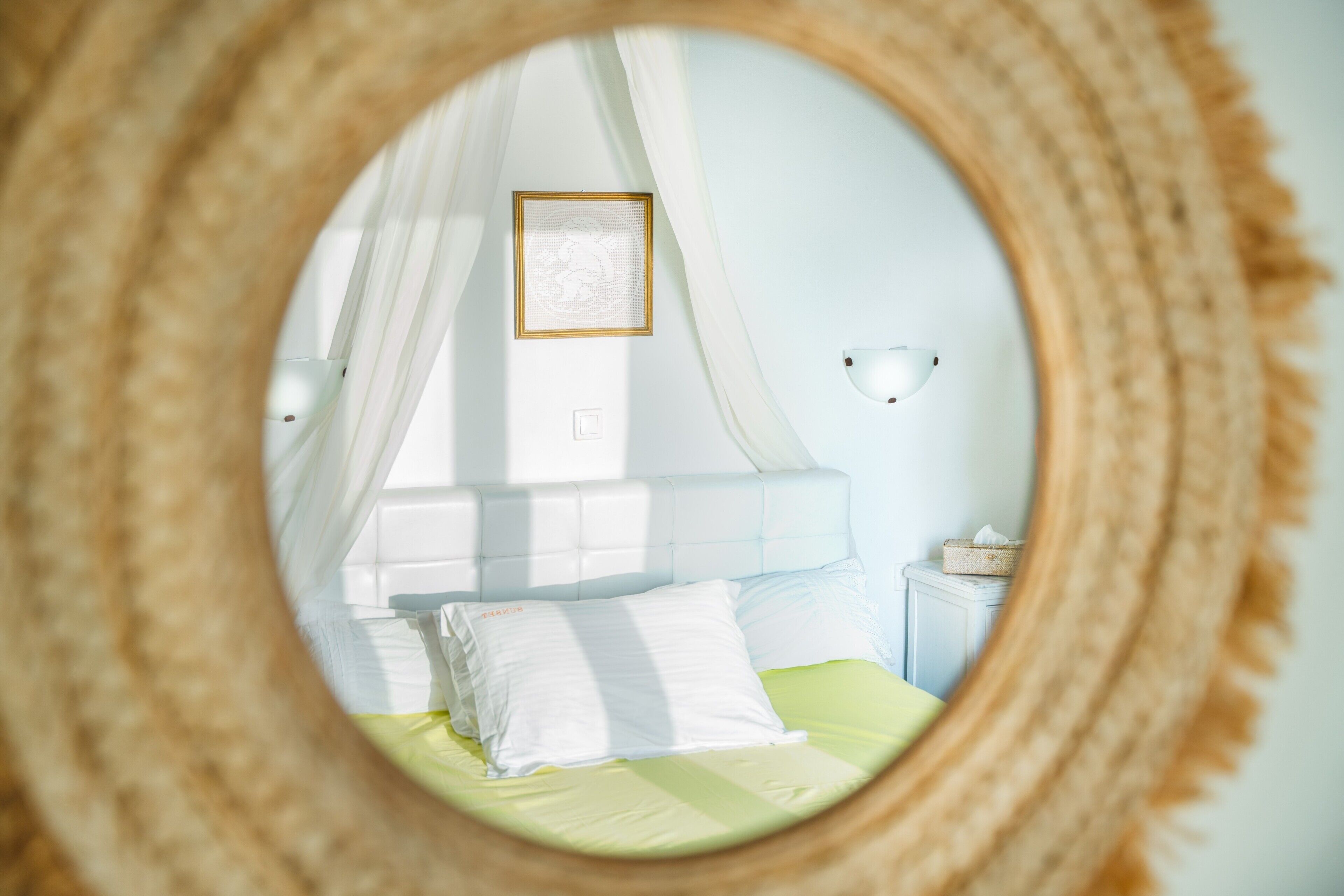 Un dormitorio con una cama, una mesita de noche, una lámpara de pared y un cuadro enmarcado.